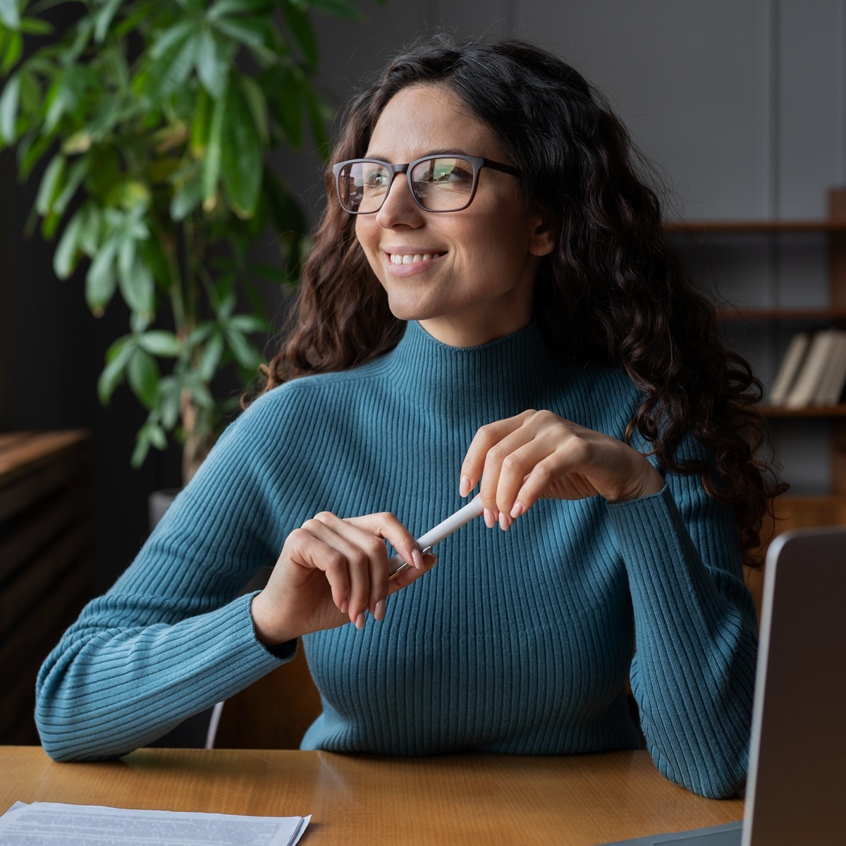 A woman sitting down holding a pen